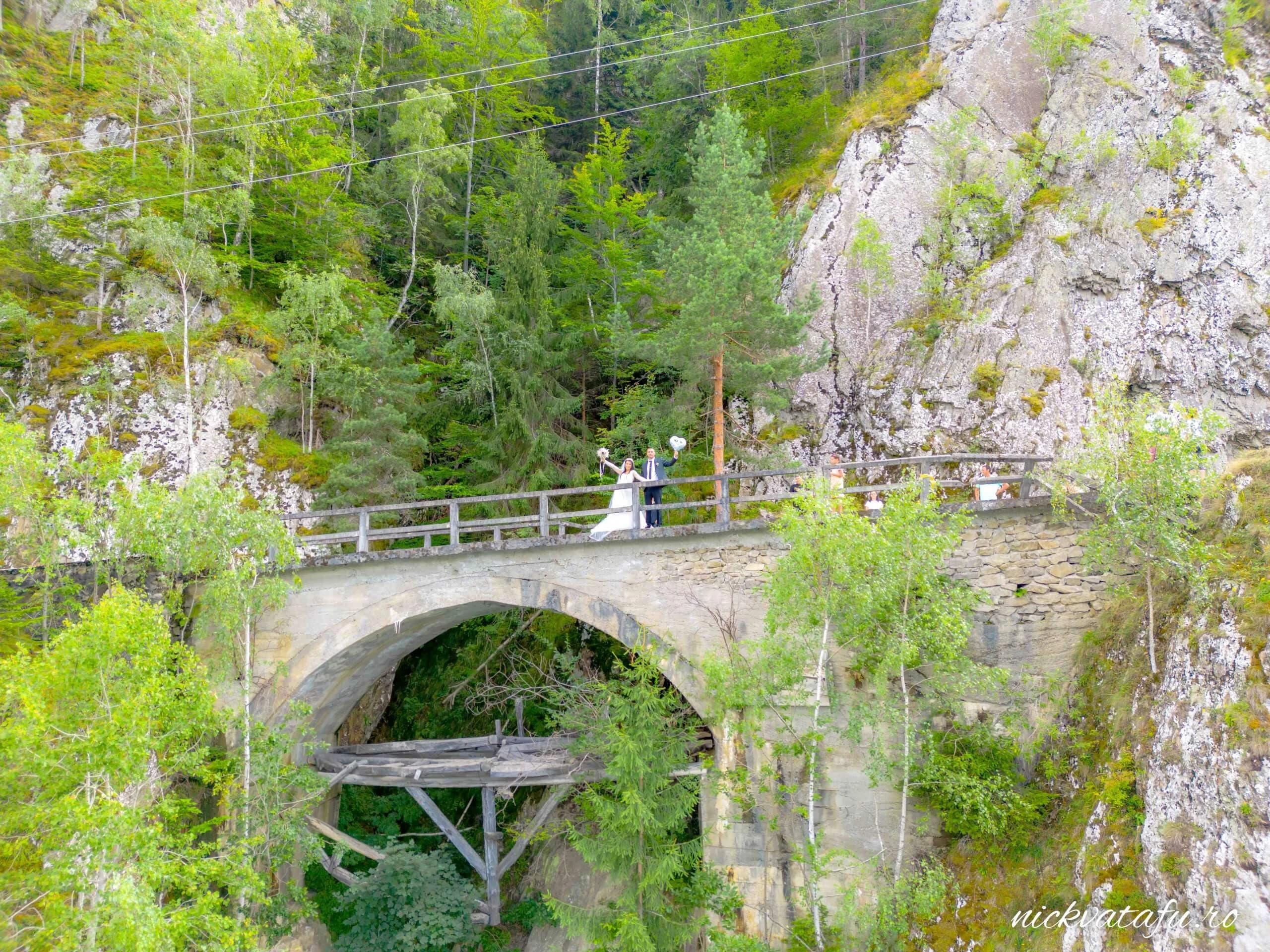 Vedere aeriana cu miri pe podul de piatra la nunta, fotografiata cu drona
