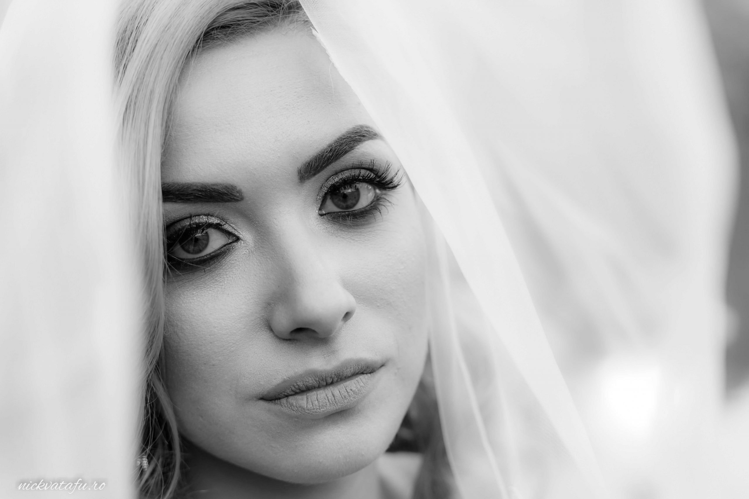 Mireasă cu voal, privire intensă și emoție profundă, fotografie de nuntă în alb și negru.