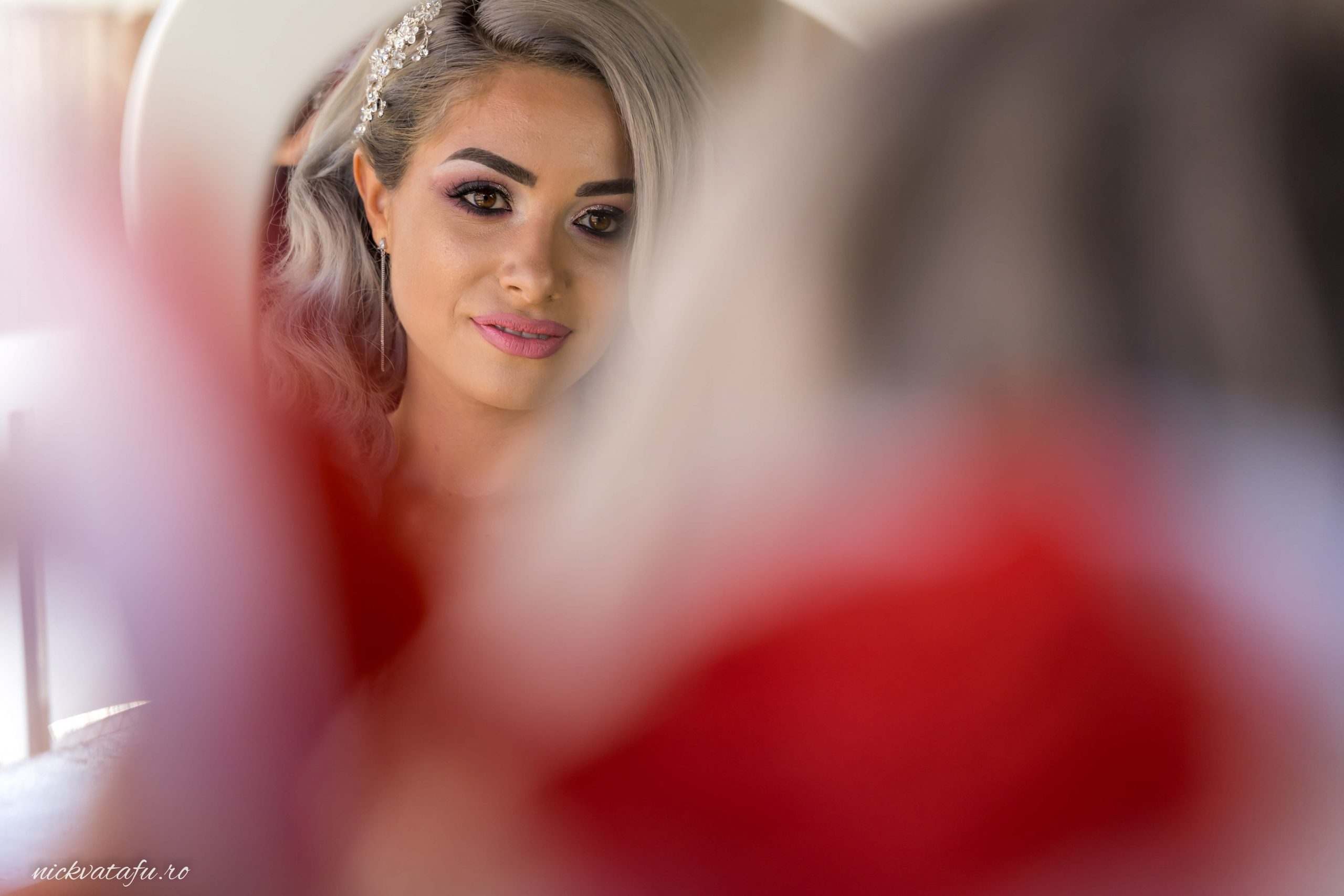 Mireasă zâmbitoare admirându-se în oglindă, detalii elegante pentru o fotografie de nuntă plină de emoție.