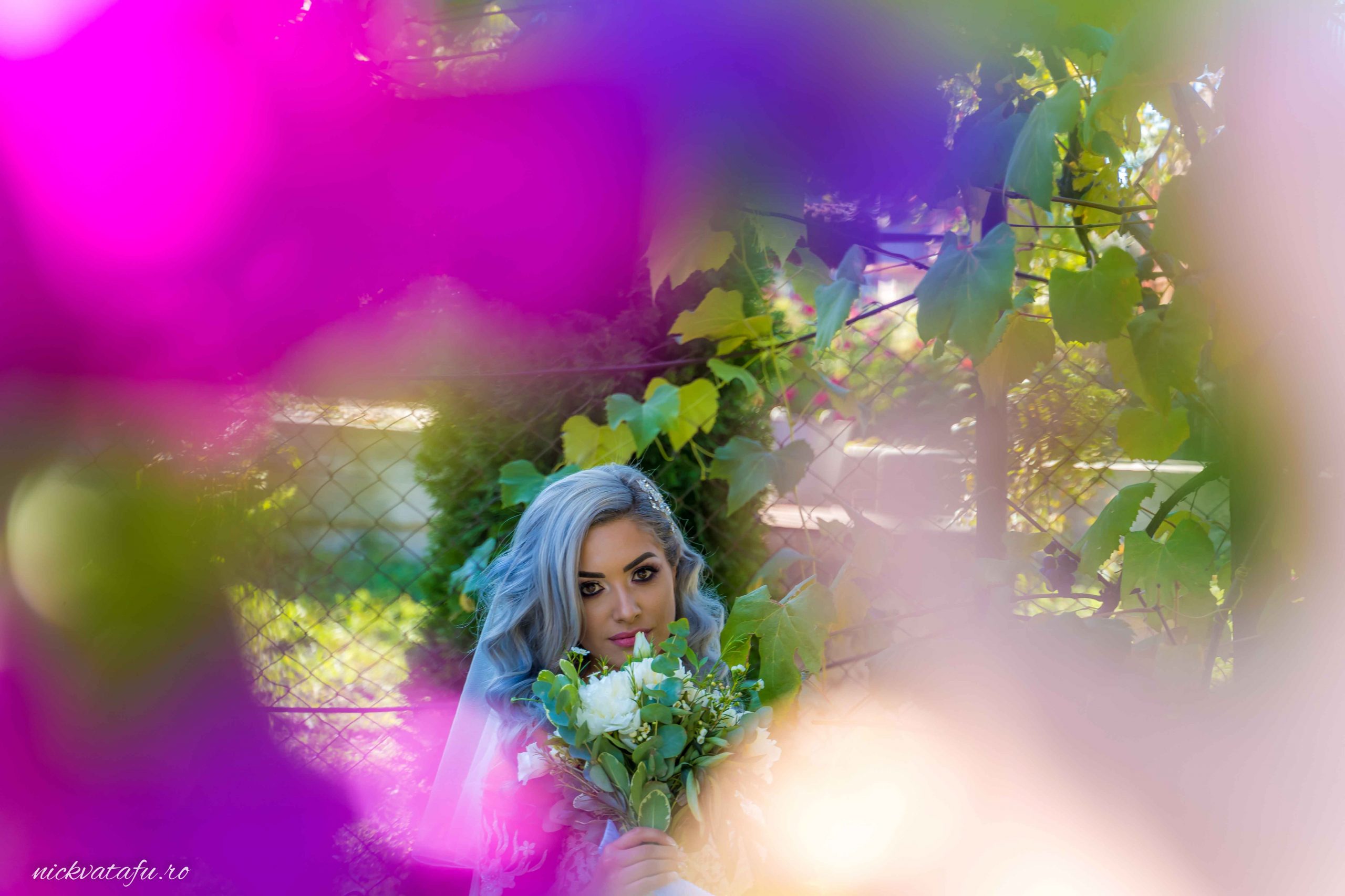 Mireasă cu buchet de flori, înconjurată de flori colorate, capturând emoția unei zile speciale de nuntă.