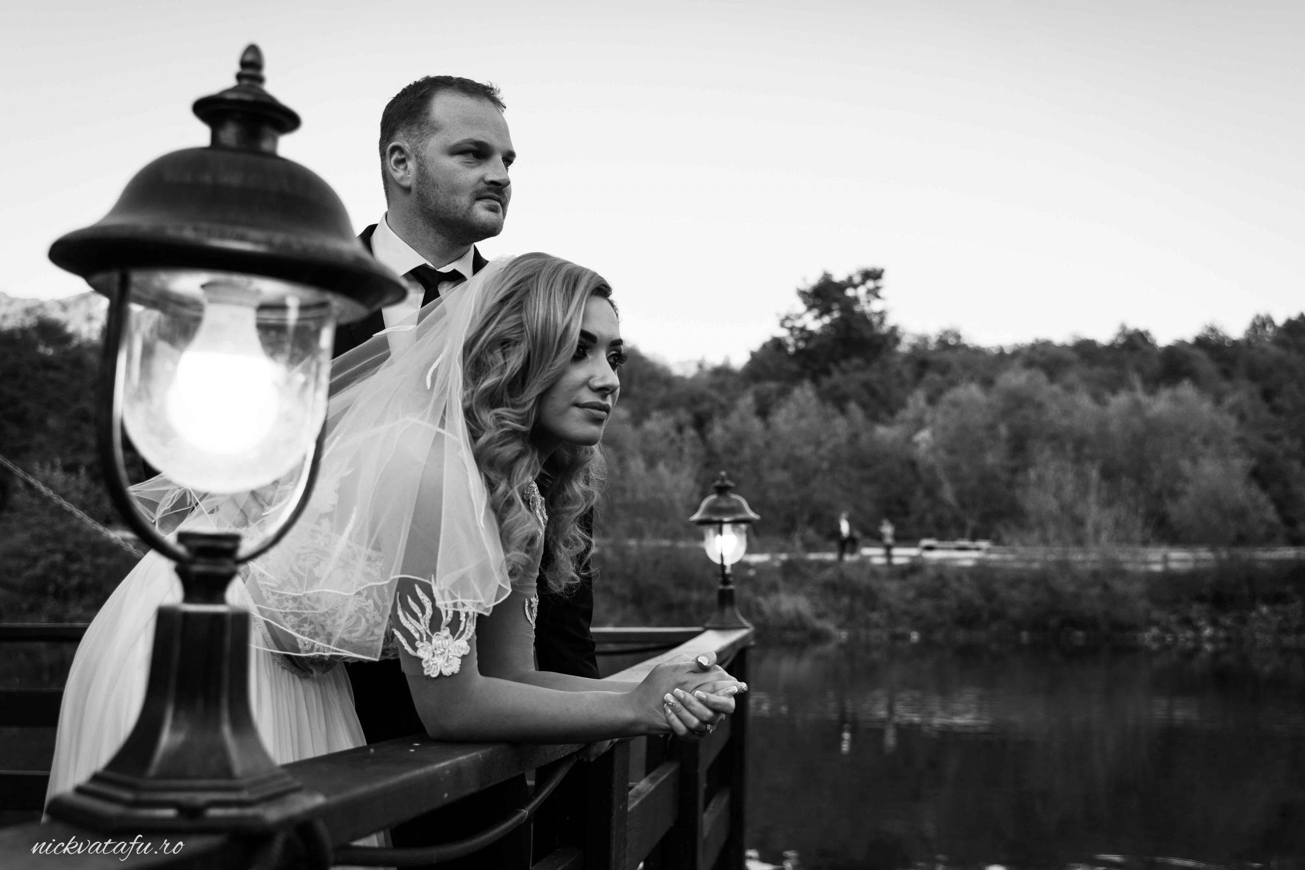 Mire și mireasă admirând peisajul lacului, într-o fotografie de nuntă plină de emoție și romantism.