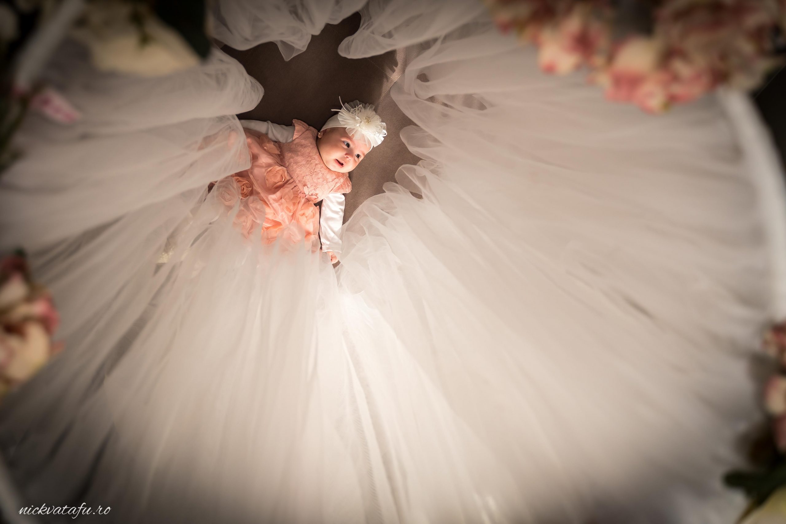 Fetiță purtând o rochie elegantă de mireasă, înconjurată de voaluri delicate, emanând bucurie și emoție.