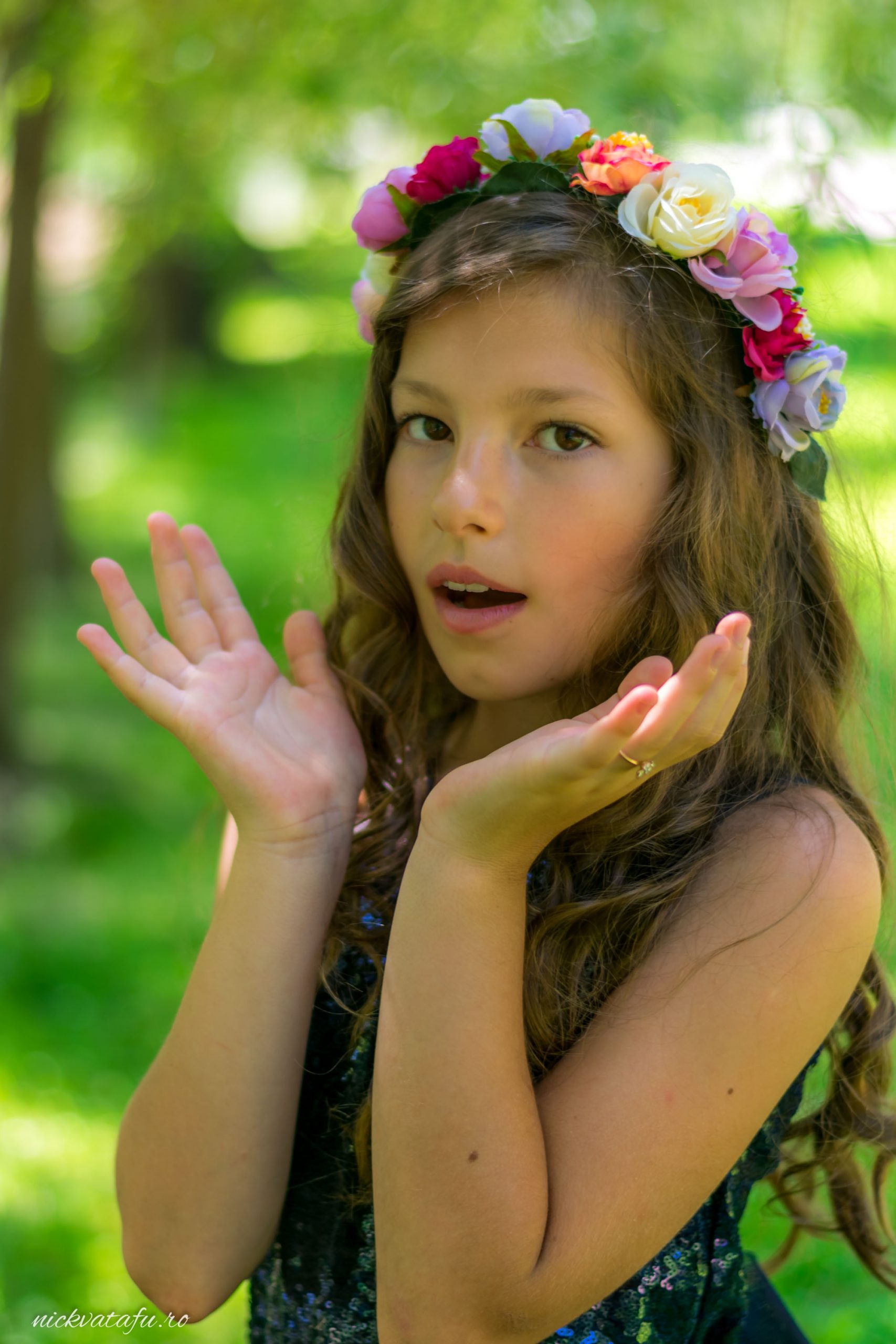 Fetiță cu coroană de flori, exprimând uimire într-un decor natural, fotografie de eveniment plină de emoție.