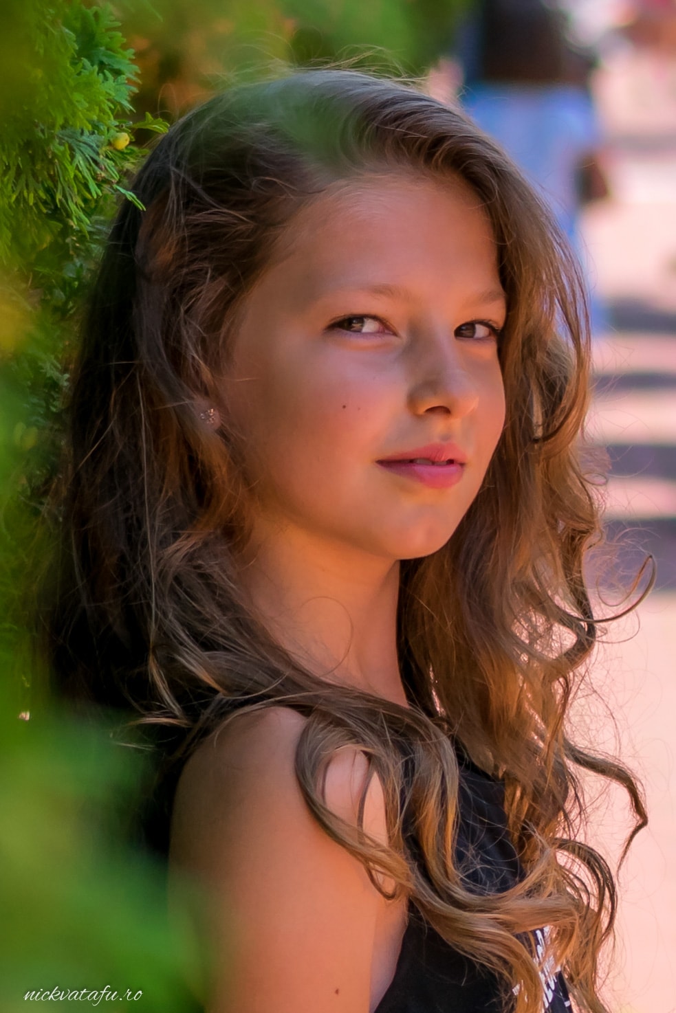 Tânără cu păr ondulat, privire contemplativă, iluminată natural, perfectă pentru o fotografie de portret elegantă.