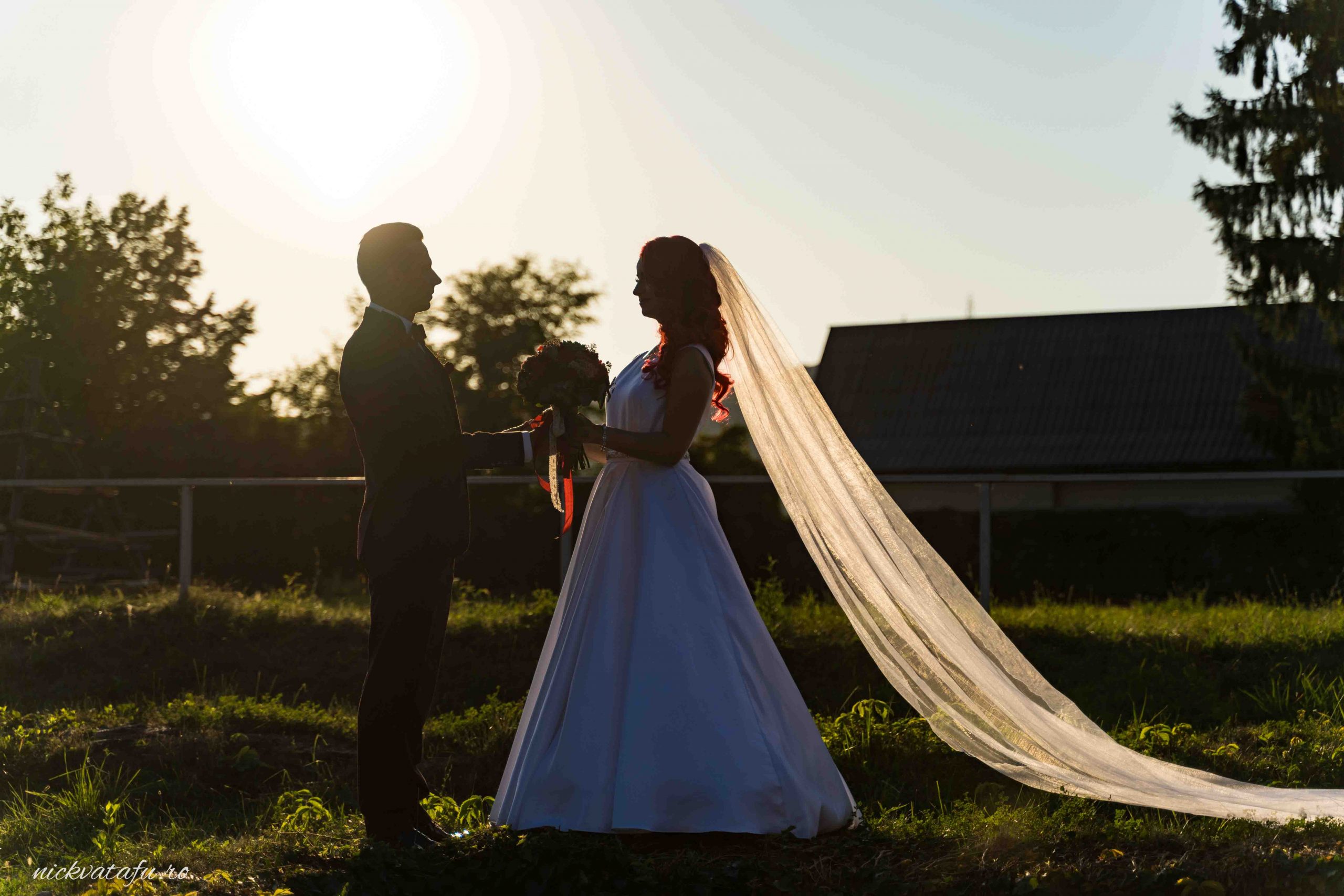Mire și mireasă se privesc cu emoție la apus, fotografie de nuntă în lumină naturală, detalii romantice.