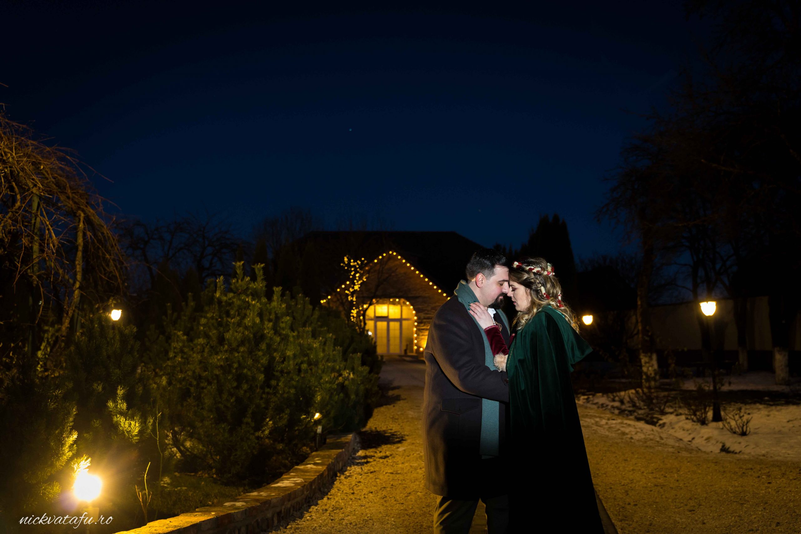 Mire și mireasă se sărută sub lumini calde, fotografie de nuntă romantică, atmosfera nocturnă de poveste.