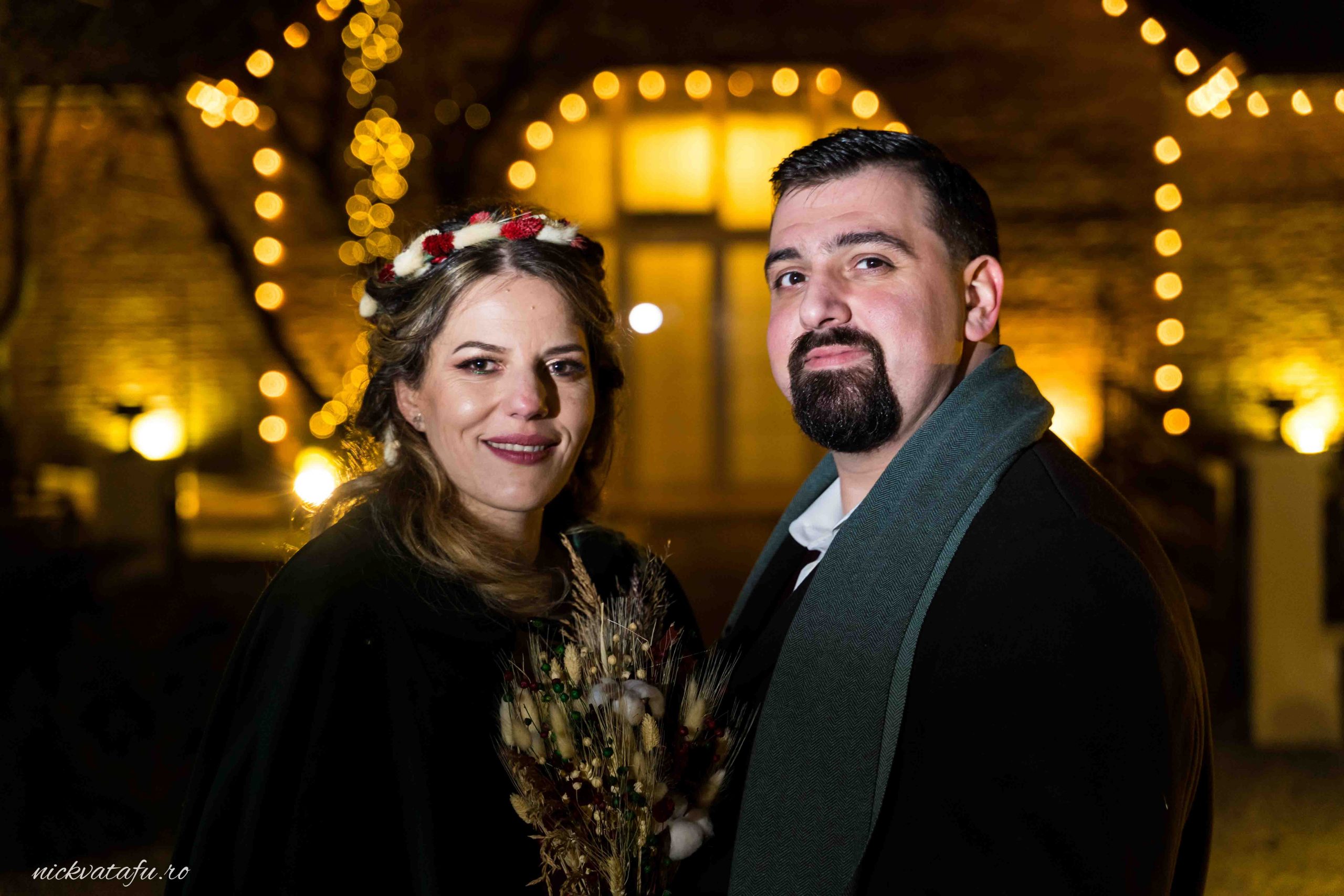 Mire și mireasă zâmbind fericiți în lumina decorativă a unei locații de nuntă, emoție și intimitate.