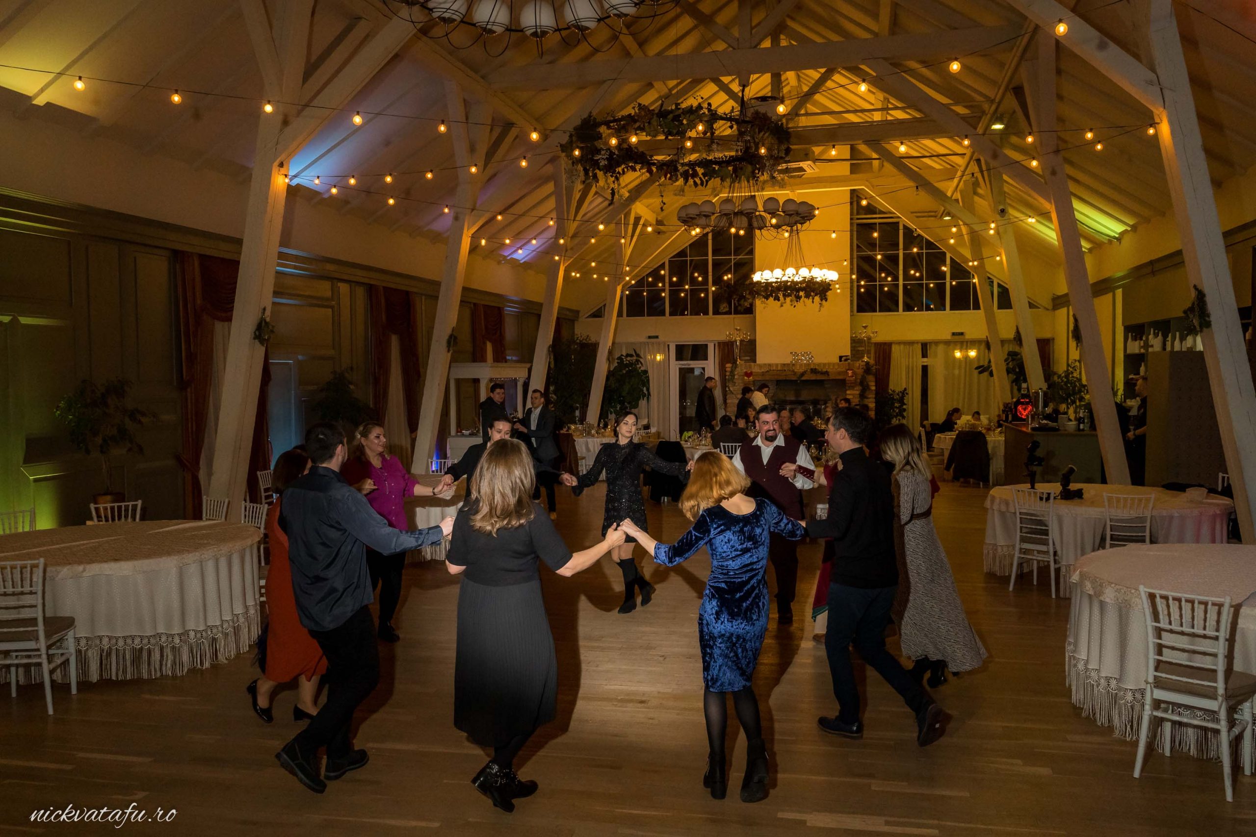 Petrecere plină de energie cu invitați dansând într-o atmosferă festivă, fotografie de nuntă elegantă.