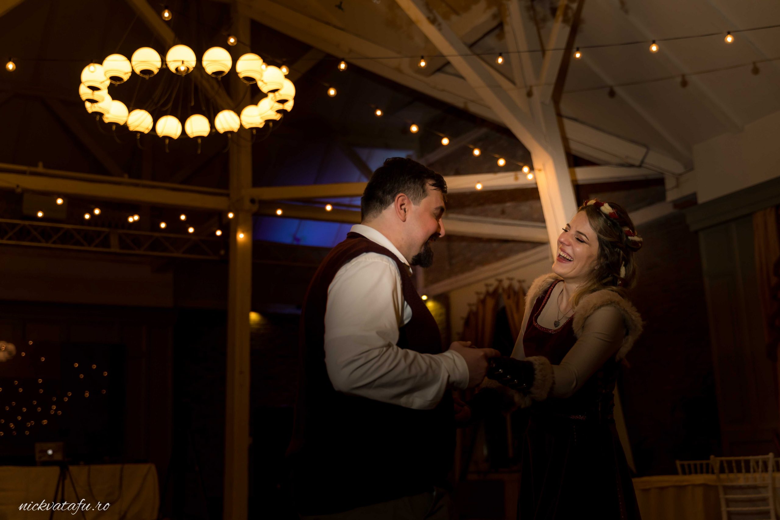 Zâmbete și priviri pline de emoție între doi îndrăgostiți, într-o atmosferă romantică de nuntă.