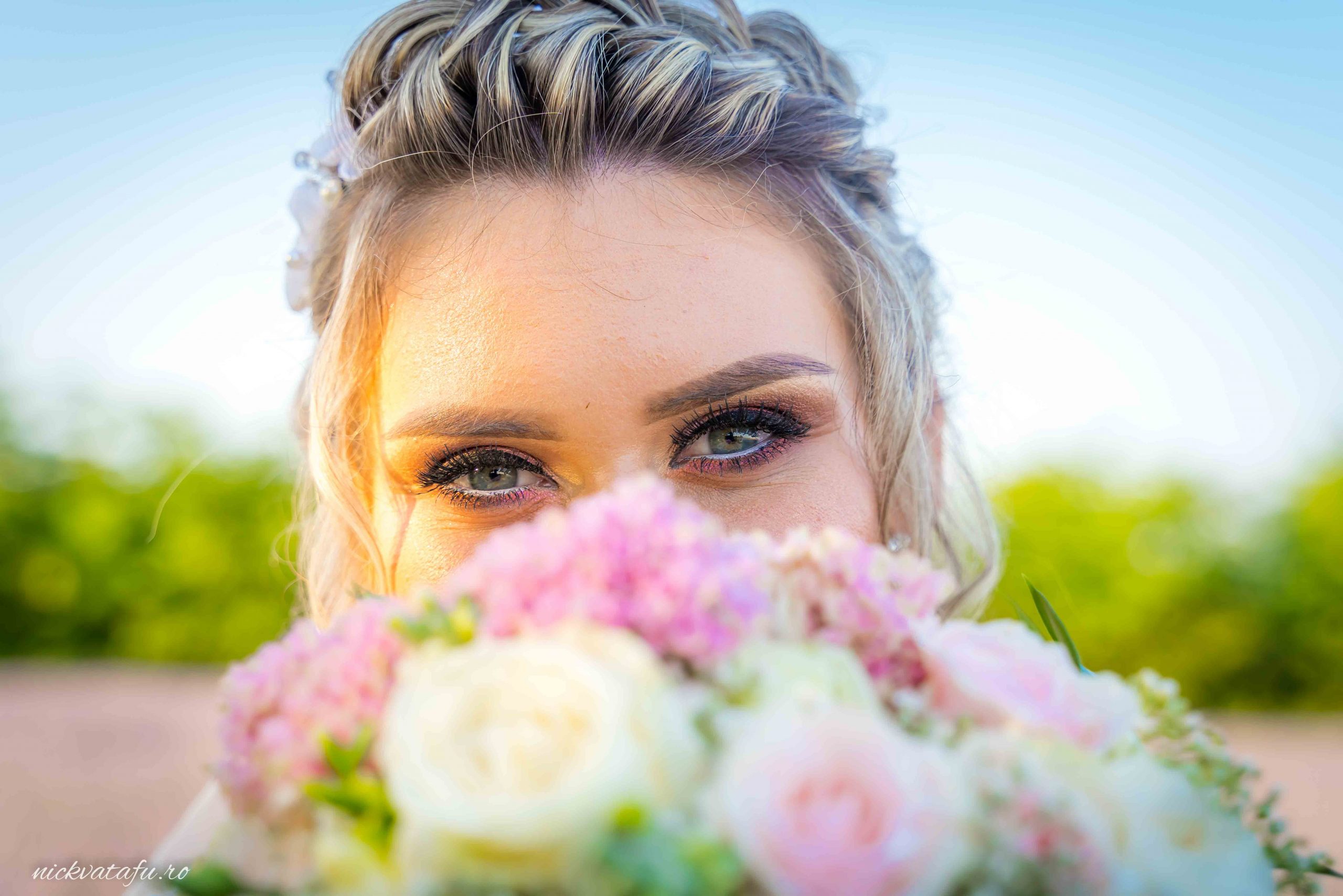 Mireasă cu buchet de flori, zâmbind cu emoție, capturată într-o fotografie nuntă plină de culoare și naturalețe.