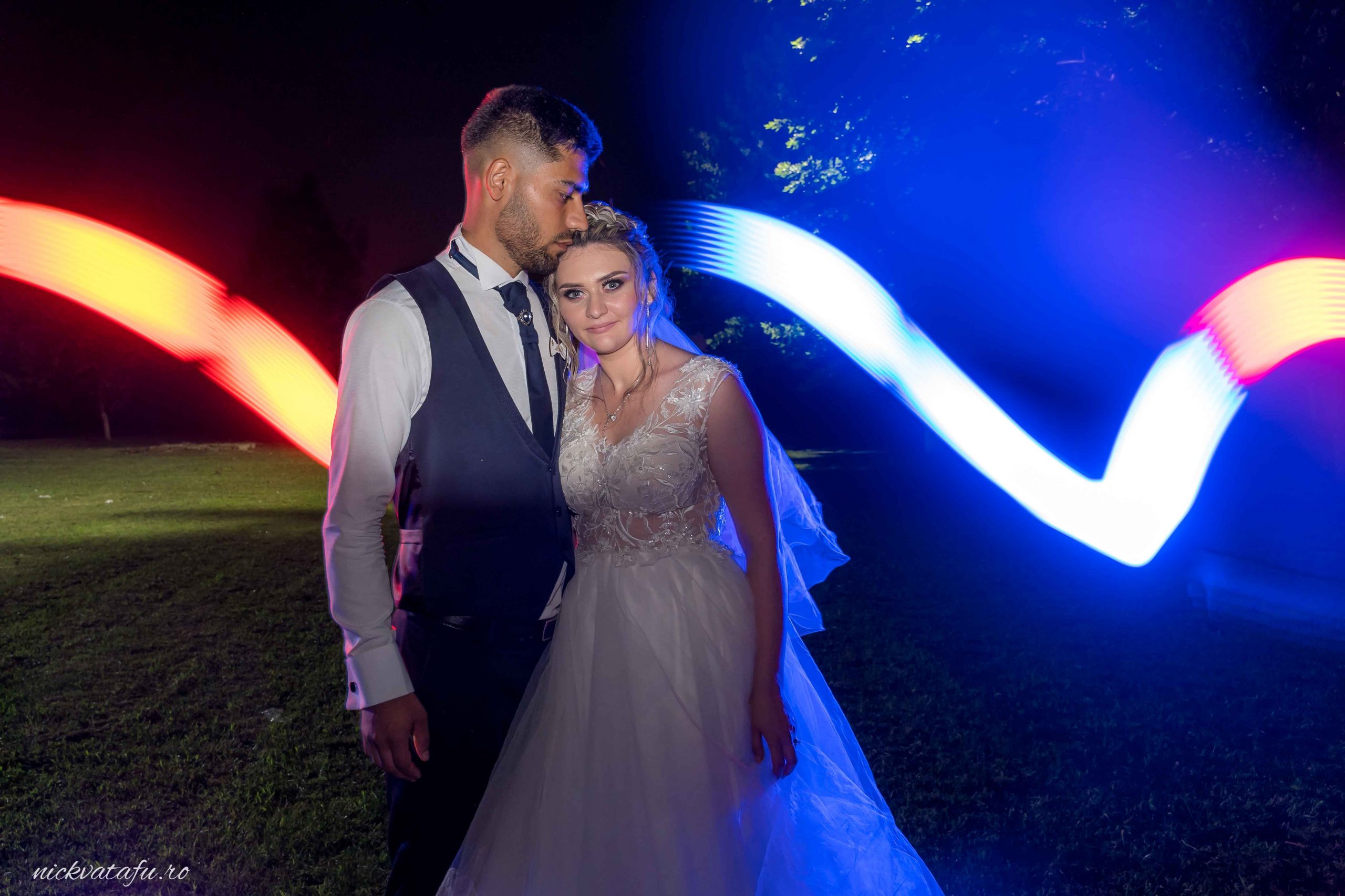 Mire și mireasă într-un moment intim sub lumini colorate, fotografie de nuntă plină de emoție.